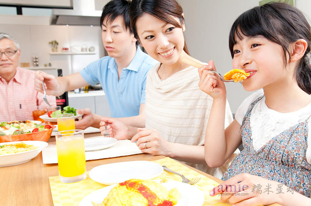 家人在餐桌母親開心的,看著女兒在吃飯