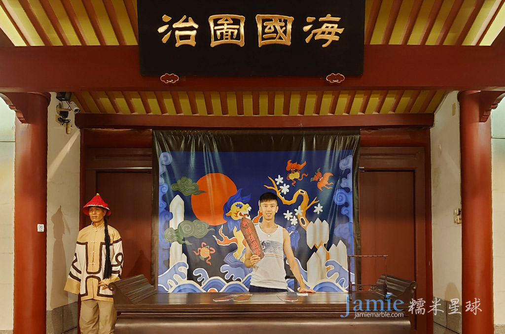 糯米部落客拿著拍照用的令牌,上面匾額寫著-治圖國海