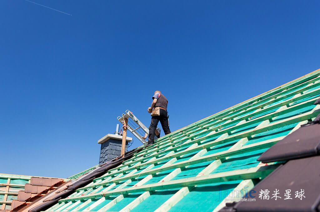 工人在修理綠色的瓦片屋頂